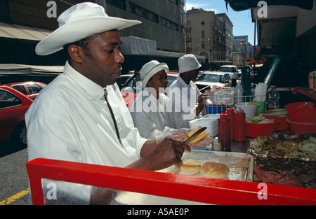 Un vendeur de sandwich à Johannesburg beurrer un morceau de pain Banque D'Images