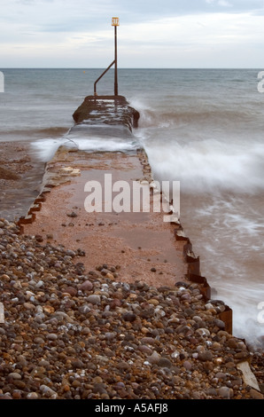 Vagues se brisant sur un épi d'acier et de béton sur la plage de Sidmouth, Devon, Angleterre. Banque D'Images