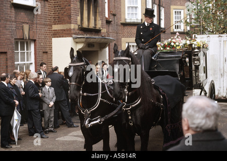 Corbillard tiré par des chevaux avec cercueil et fleurs conduit par l'homme en haut de forme et des vêtements de deuil Banque D'Images