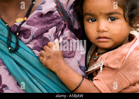 Close up portrait of Indian enfant pauvre sur la hanche de sa mère dans un sling Banque D'Images