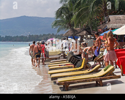 Trois jeunes femmes se préparent à prendre le soleil sur les chaises longues de l'île Ko Samui Chaweng Beach, Thaïlande Banque D'Images