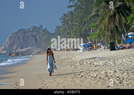 Femme en robe bleue longue promenades tôt le matin sur la plage de Lamai Ko Samui Island Thailand Banque D'Images