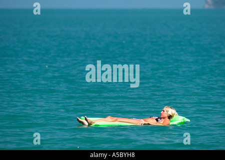 Jeune femme blonde bikini vert brillant flotte sur lit d'air au large de la plage de Bophut Ko Samui Island Thailand Banque D'Images