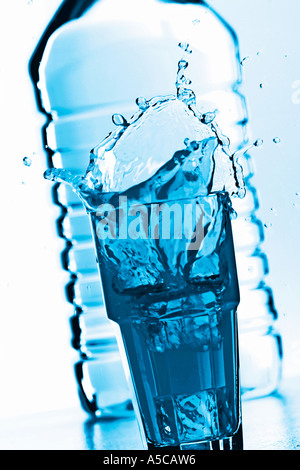 Glas éclaboussures d'eau devant une bouteille Banque D'Images