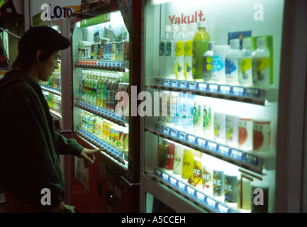 Un jeune homme choisit une boisson à l'un des nombreux distributeurs automatiques japonais. Machida, Tokyo, Japon Banque D'Images