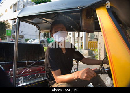 Protection du smog dans la capitale animée de Bangkok, Thaïlande. Chauffeur de taxi tuk-tuks portant masque à filtre la pollution des gaz d'échappement du véhicule de filtrage. Banque D'Images