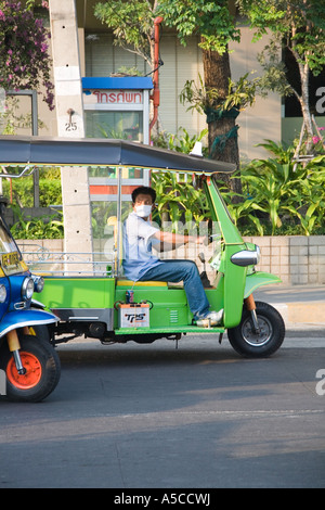 Le conducteur de Tuk-tuks à Bangkok porte un masque de filtre anti-pollution comme protection contre le smog de la circulation routière et l'échappement des véhicules. Banque D'Images