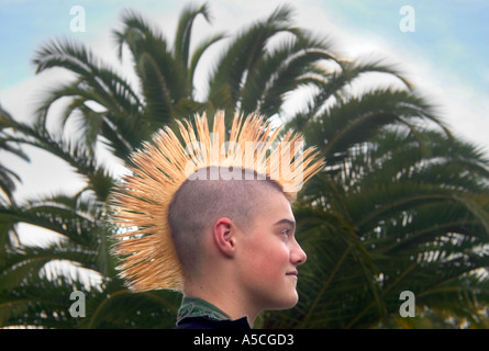 Une couleur horizontal image d'un garçon avec un grand Mohawk jaune dans le profil en face d'un grand palmier vert Banque D'Images