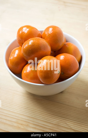 Les satsumas en blanc bol sur table en bois Banque D'Images