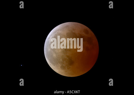 Lune devient moins rouge qu'il sort de l'ombre de la terre juste après la totalité durant éclipse lunaire totale en cours Banque D'Images