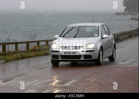 Vw golf argent voiture avec les phares et les essuie-glaces sur les lecteurs le long de la route côtière sur un jour de tempête Portaferry county down Banque D'Images