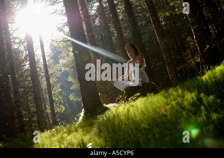 Jeune femme médiation en forêt, low angle view Banque D'Images