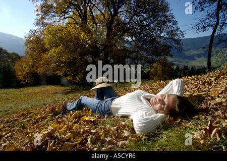 Jeune femme couchée sur les feuilles d'automne, portrait Banque D'Images