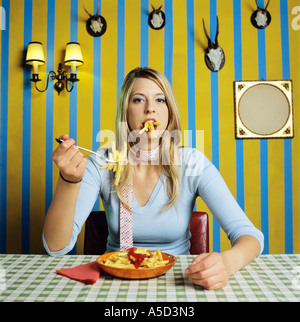 Young woman eating french fries Banque D'Images