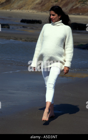 Femme enceinte asiatique anglo habillé en blanc le long de la plage à pied aux beaux jours Banque D'Images