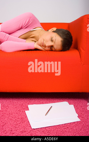 Femme fatiguée de dormir sur le canapé rouge papiers sur le plancher Banque D'Images