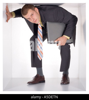 Businessman with laptop à l'étroit dans le cube blanc Banque D'Images