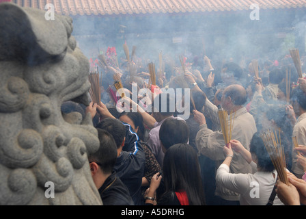 Soleil brûlant holding joss sticks pendant les célébrations du Nouvel An lunaire dans le temple de Wong Tai Sin, Kowloon. Hong Kong, Chine Banque D'Images