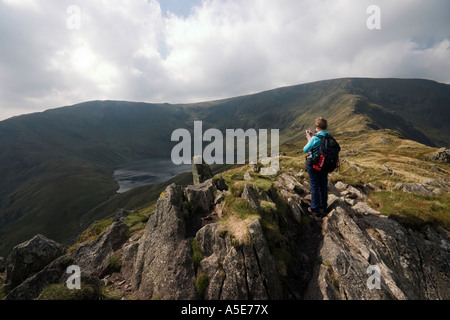 Vu de l'eau Blea Crag rugueux Haweswater une dame walker prend une photo de la scène Banque D'Images