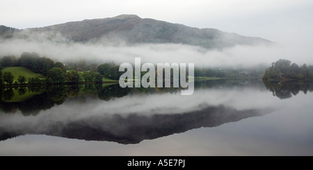 Réflexions dans un lac Grassmere encore sur un matin brumeux Banque D'Images