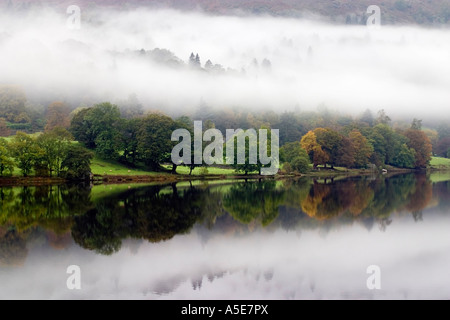 Réflexions dans un lac Grassmere encore sur un matin brumeux Banque D'Images