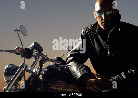 Portrait d'homme avec veste en cuir et des lunettes de soleil assis sur moto Harley Banque D'Images