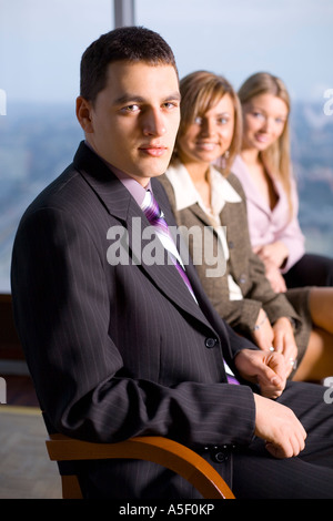 Groupe de personnes regardant la caméra se concentrer sur le visage de la première personne s'il n'y Grande fenêtre avec vue sur la grande ville derrière eux Banque D'Images