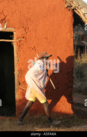 Ambalavao, Madagascar, Farmer Walking en face d'une maison d'argile rouge Banque D'Images