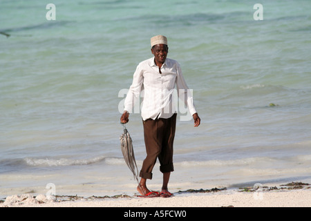 Zanzibar : homme portant un calmar sur la plage de sable blanc sur la côte est, la Tanzanie, l'Afrique Banque D'Images