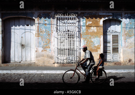 L'homme chevauche son jeune fille en bicyclette à travers les rues de Trinidad Cuba Antilles Banque D'Images