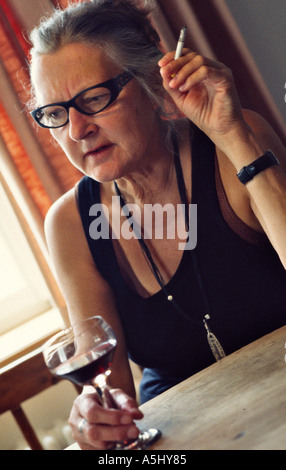 Monsieur vieille femme de boire du vin rouge et fumer une cigarette Banque D'Images