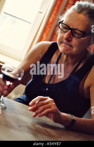 Monsieur vieille femme de boire du vin rouge et fumer une cigarette Banque D'Images