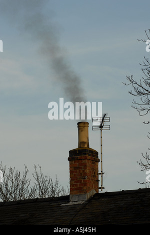La fumée d'un feu de charbon laisse une cheminée au crépuscule, en hiver. Banque D'Images