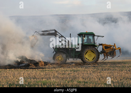 Brûler le chaume et le tracteur dans le champ, East Lothian, UK Banque D'Images