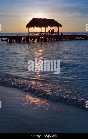 'Pigeon Point' plage au coucher du soleil, Tobago, île des Caraïbes, la silhouette de la célèbre jetée de chaume et calme mer tropical Banque D'Images