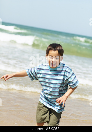 Jeune garçon jouant running on beach Banque D'Images