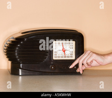 Femme tournant le bouton sur la radio à l'ancienne Banque D'Images