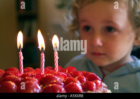 Trois ans, fille enfant faisant un vœu avant de souffler les bougies sur son gâteau d'anniversaire Banque D'Images