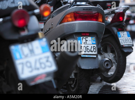 Nombre de plaques de cyclomoteurs garés dans une ligne sur une rue de Rome Italie Banque D'Images