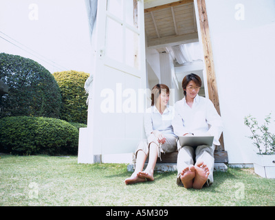 Asian couple assis à la porte Banque D'Images