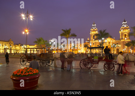 Voitures à cheval sur la Plaza Mayor au crépuscule avec la Cathédrale Lima Pérou Banque D'Images