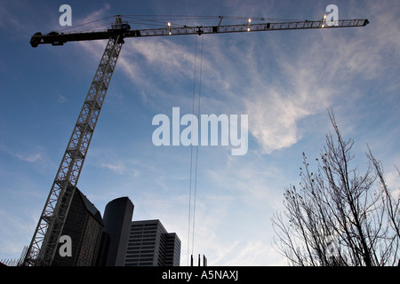 Quart de soir une grande grue avec projecteurs de la rampe le long de la silhouette sur un ciel bleu et nuages vaporeux éclairée par un soleil couchant Banque D'Images
