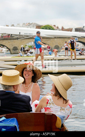 Des spectateurs qui préservent les traditions édouardiennes de la régate royale de Henley assis dans le skiff avec des équipages derrière la rive, en Angleterre Banque D'Images