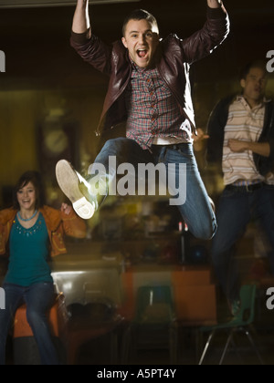 Jeune homme sautant dans l'excitation dans un bowling Banque D'Images