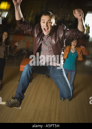 Jeune homme sautant dans l'excitation dans un bowling Banque D'Images