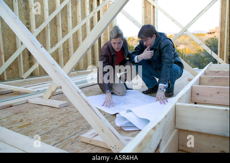 Jeune couple looking at blueprints dans leur construction site Banque D'Images