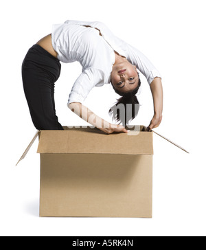 Female contortionist businesswoman inside cardboard box Banque D'Images