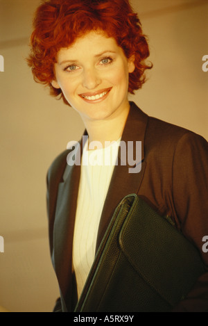 Businesswoman standing with briefcase underarm, portrait Banque D'Images