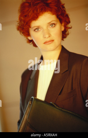 Businesswoman standing with briefcase underarm, portrait Banque D'Images