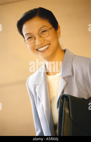 Businesswoman standing with briefcase underarm, portrait Banque D'Images